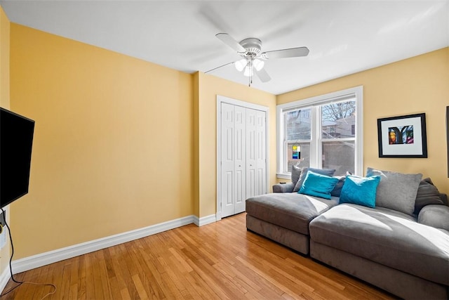 living room featuring light wood-type flooring, a ceiling fan, and baseboards