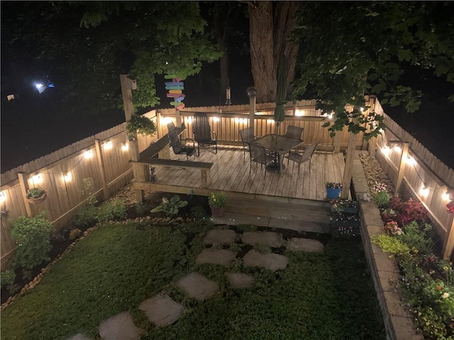 deck at twilight featuring a fenced backyard and outdoor dining area