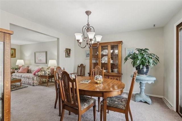 carpeted dining room with baseboards and an inviting chandelier