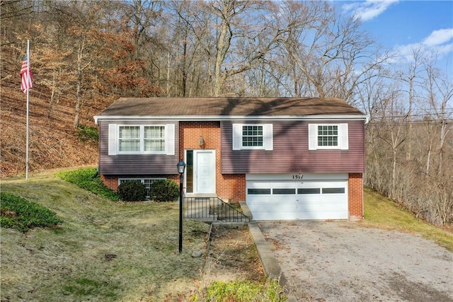 raised ranch with a garage, driveway, brick siding, and a front yard