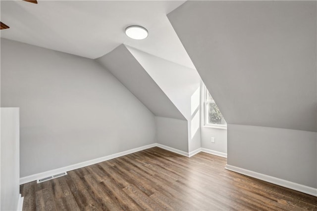 additional living space with visible vents, lofted ceiling, baseboards, and wood finished floors