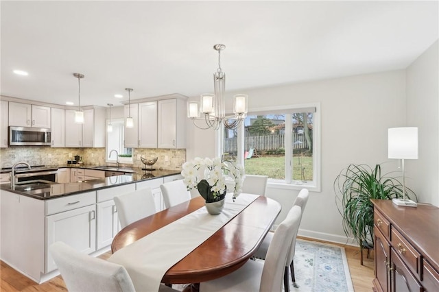 dining space with plenty of natural light, baseboards, light wood-style flooring, and a notable chandelier