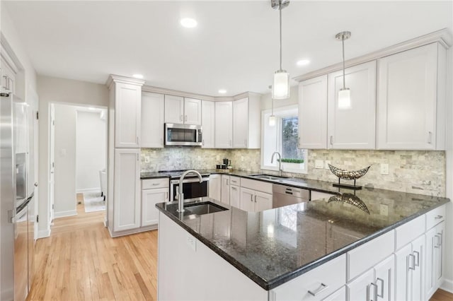 kitchen with light wood finished floors, tasteful backsplash, stainless steel appliances, and a sink