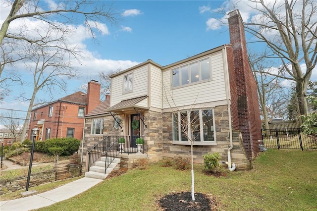 view of front of house with a front yard, stone siding, fence, and a chimney