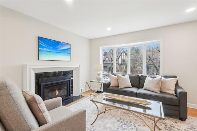 living area featuring recessed lighting, a fireplace, baseboards, and wood finished floors