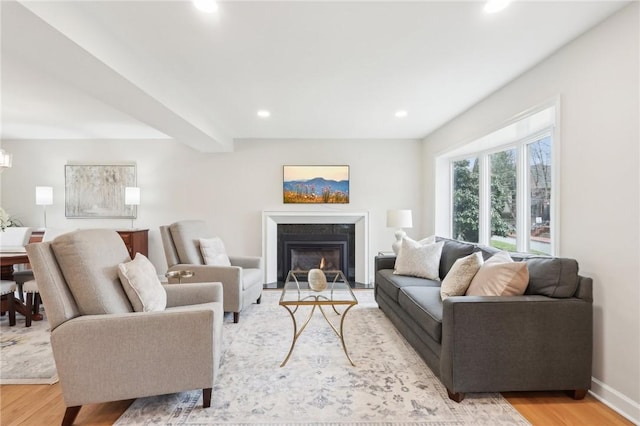 living room featuring baseboards, a fireplace with flush hearth, light wood-type flooring, beam ceiling, and recessed lighting