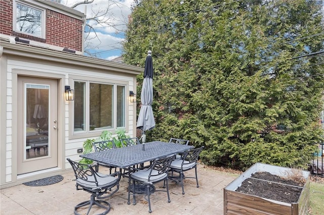 view of patio with outdoor dining space and a garden