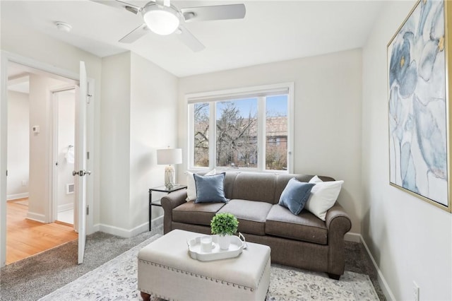 living area with ceiling fan, light carpet, and baseboards