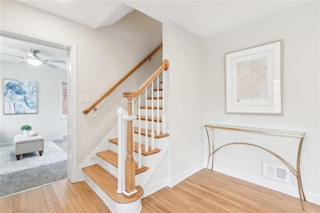 stairs featuring ceiling fan, wood finished floors, visible vents, and baseboards