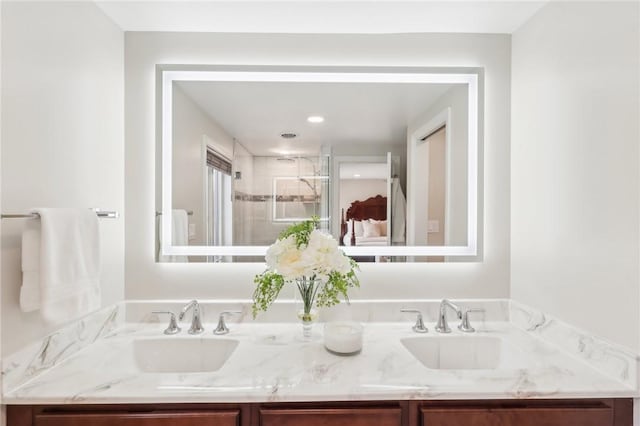 bathroom featuring double vanity, a stall shower, and a sink