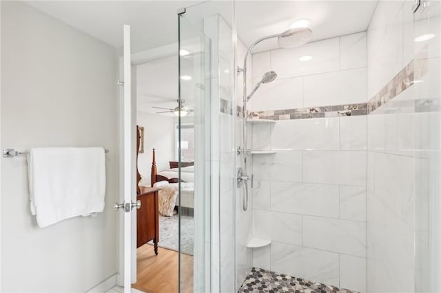 bathroom with connected bathroom, a shower stall, and wood finished floors