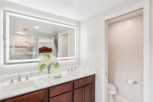 full bath with toilet, a stall shower, double vanity, and a sink