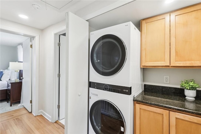 laundry area featuring stacked washing maching and dryer and light wood-style floors