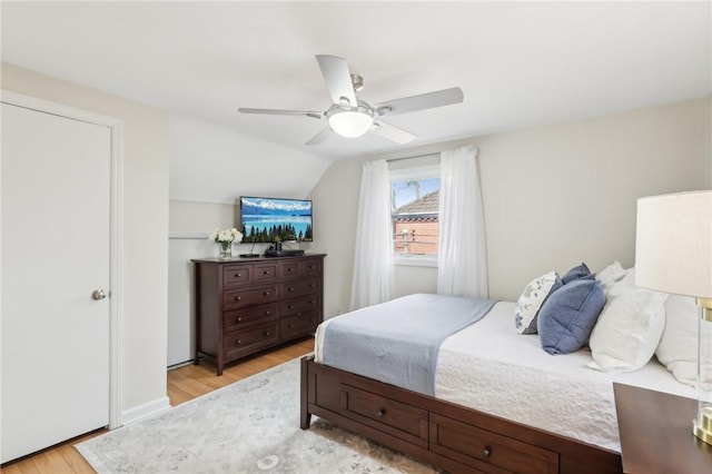 bedroom featuring a ceiling fan, light wood-type flooring, and vaulted ceiling