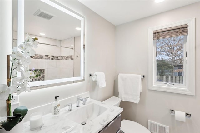 bathroom featuring toilet, vanity, a shower stall, and visible vents