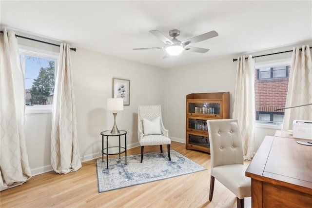 sitting room with a ceiling fan, wood finished floors, a wealth of natural light, and baseboards