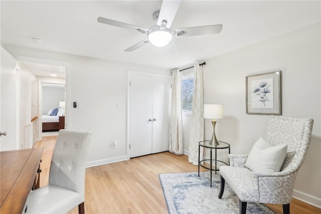 living area with ceiling fan, light wood-type flooring, and baseboards