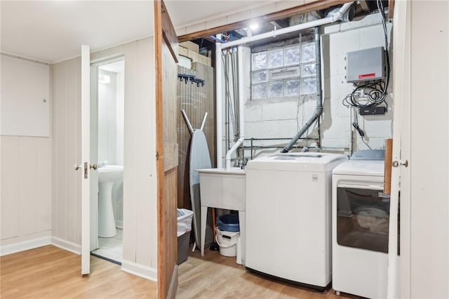 washroom featuring light wood-type flooring, laundry area, washer and dryer, and concrete block wall