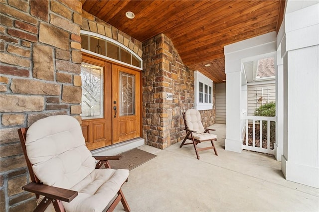 view of exterior entry featuring stone siding and a porch