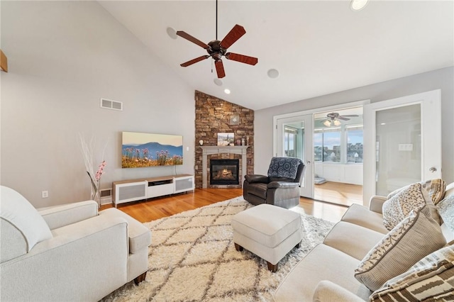 living area with visible vents, ceiling fan, wood finished floors, a fireplace, and high vaulted ceiling