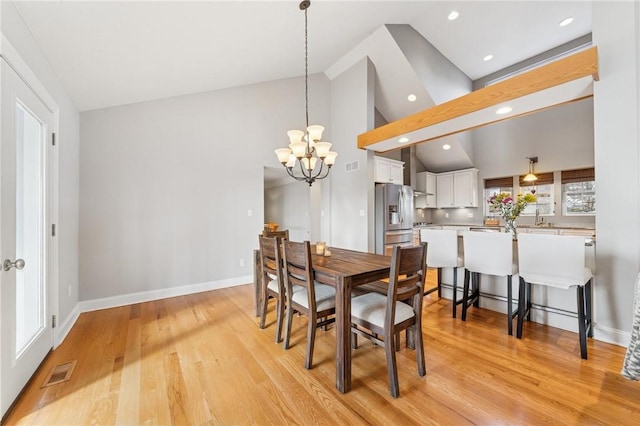 dining room with baseboards, visible vents, a notable chandelier, and light wood finished floors