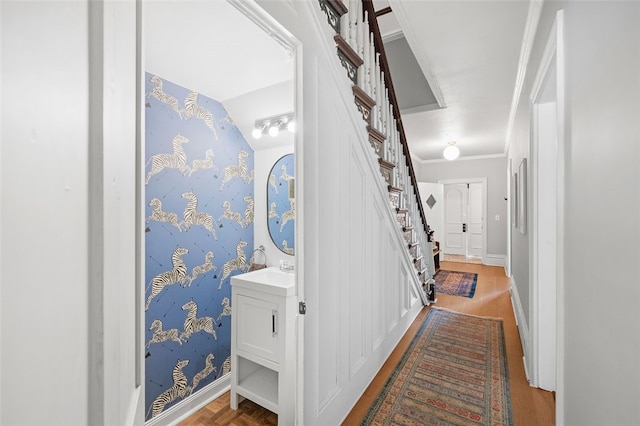 hallway featuring ornamental molding, wallpapered walls, baseboards, and stairs