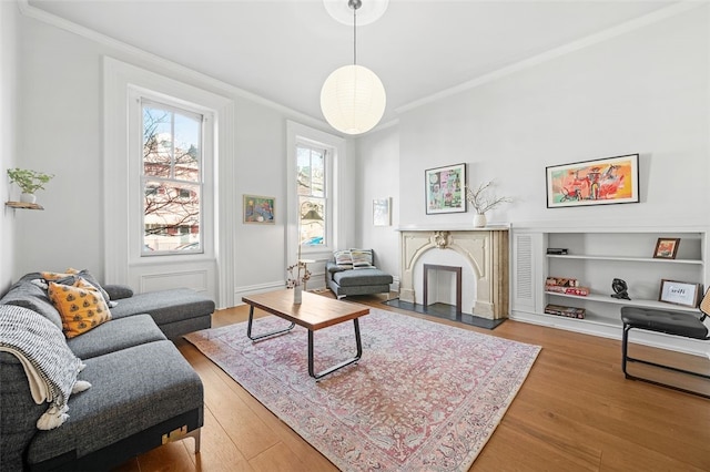 living room featuring a fireplace with flush hearth, ornamental molding, and wood finished floors