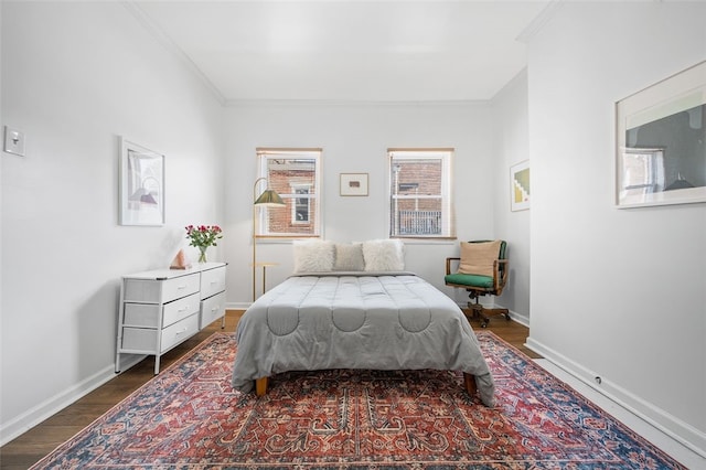 bedroom featuring dark wood-type flooring, ornamental molding, and baseboards