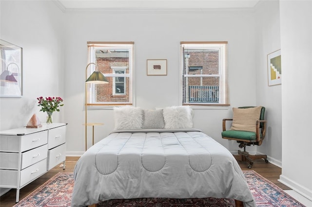 bedroom featuring baseboards, crown molding, and wood finished floors