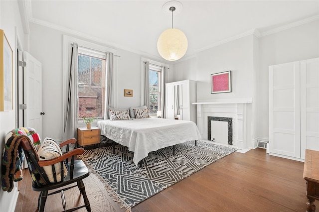 bedroom featuring a high end fireplace, crown molding, and wood finished floors