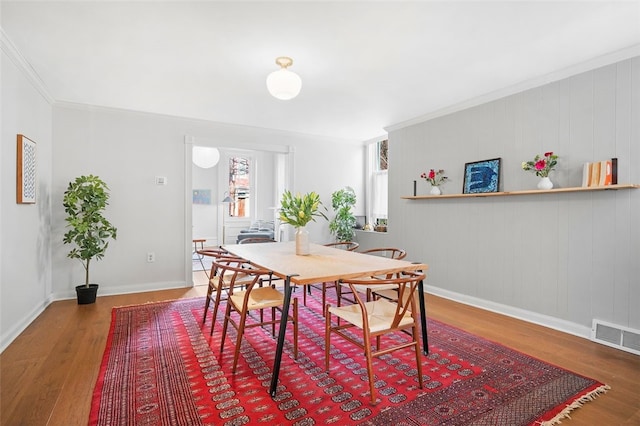 dining space with baseboards, crown molding, visible vents, and wood finished floors