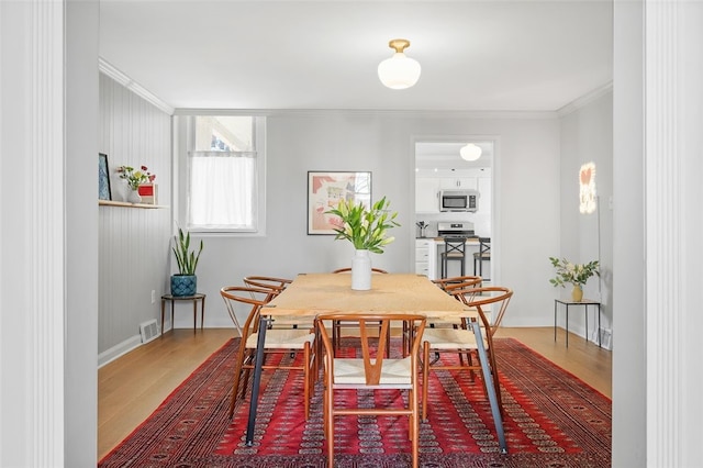 dining space with crown molding, visible vents, and wood finished floors