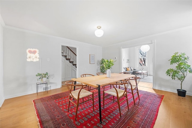 dining area featuring light wood-style flooring, stairs, visible vents, and crown molding