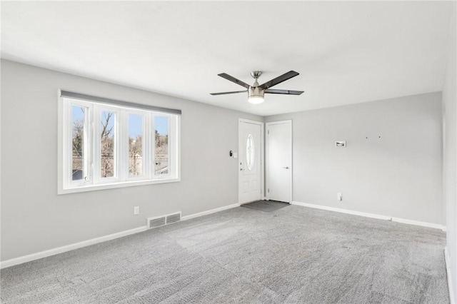 unfurnished room with carpet floors, visible vents, ceiling fan, and baseboards