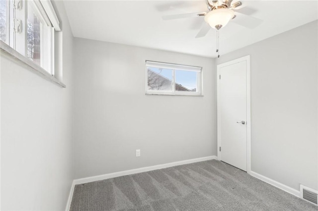 carpeted empty room with a ceiling fan, visible vents, and baseboards