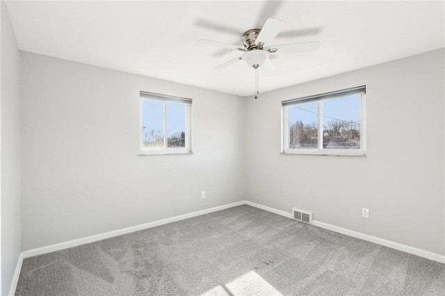 carpeted spare room with a ceiling fan, visible vents, and baseboards