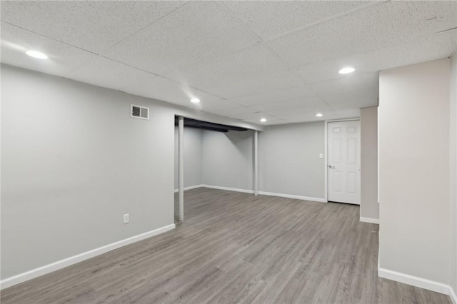 finished below grade area with recessed lighting, visible vents, wood finished floors, a drop ceiling, and baseboards