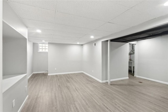 basement featuring baseboards, a drop ceiling, wood finished floors, and recessed lighting