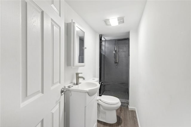 full bathroom with a stall shower, baseboards, toilet, wood finished floors, and vanity