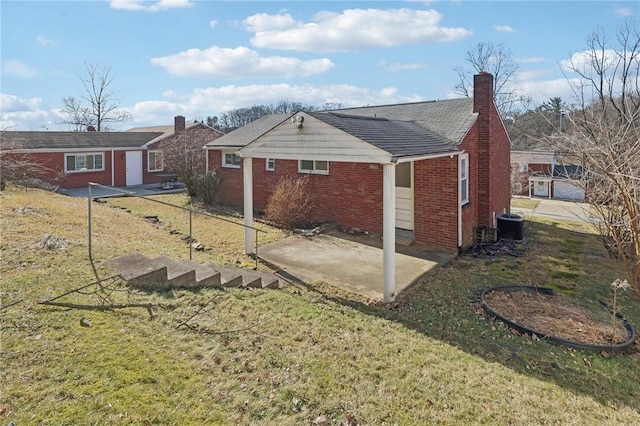 back of property with brick siding, a yard, a chimney, central air condition unit, and a patio area