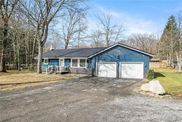 single story home featuring metal roof, an attached garage, fence, driveway, and a front yard