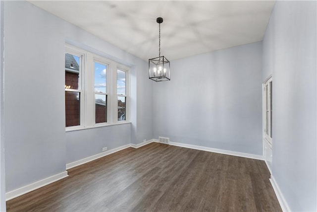 spare room with visible vents, dark wood-style floors, baseboards, and a chandelier