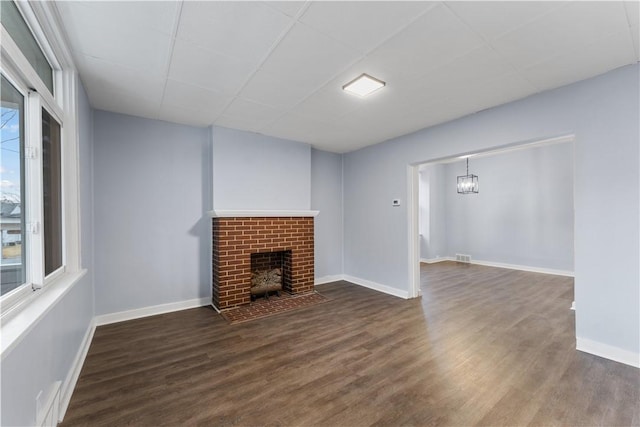 unfurnished living room with a paneled ceiling, baseboards, wood finished floors, and a fireplace