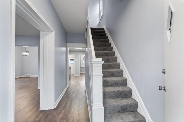 staircase featuring wood finished floors, visible vents, and baseboards