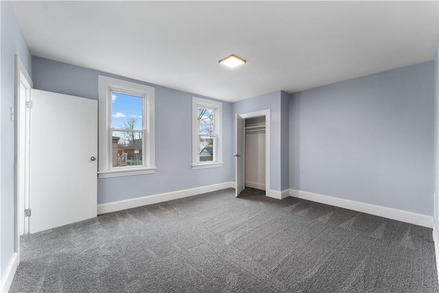 unfurnished bedroom featuring dark colored carpet, a closet, and baseboards