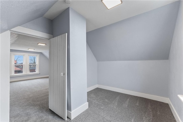 additional living space with baseboards, carpet, and vaulted ceiling