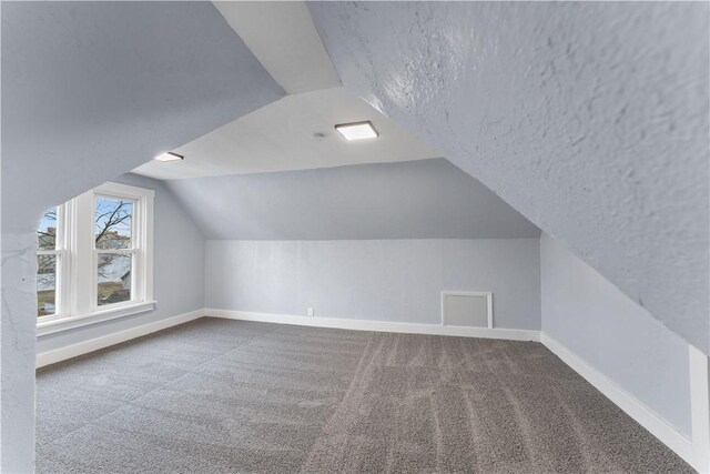 bonus room with lofted ceiling, carpet flooring, baseboards, and a textured ceiling