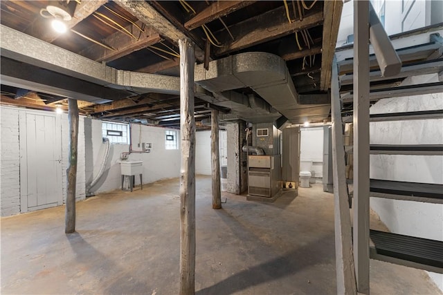 basement featuring a sink, visible vents, and heating unit