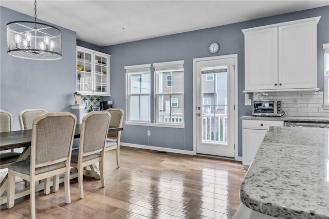 dining area featuring baseboards, a toaster, light wood-style flooring, and an inviting chandelier