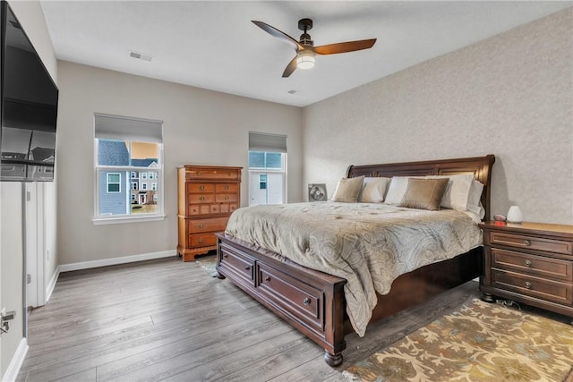 bedroom featuring a ceiling fan, light wood-type flooring, visible vents, and baseboards